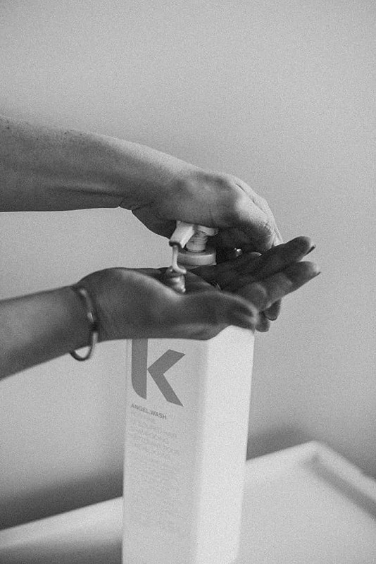 Hands using a Kevin Murphy brand hand pump of hair product