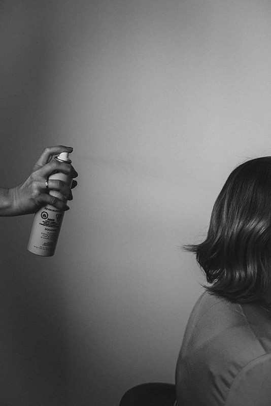Spraying Kevin Murphy hair product on a client’s hair