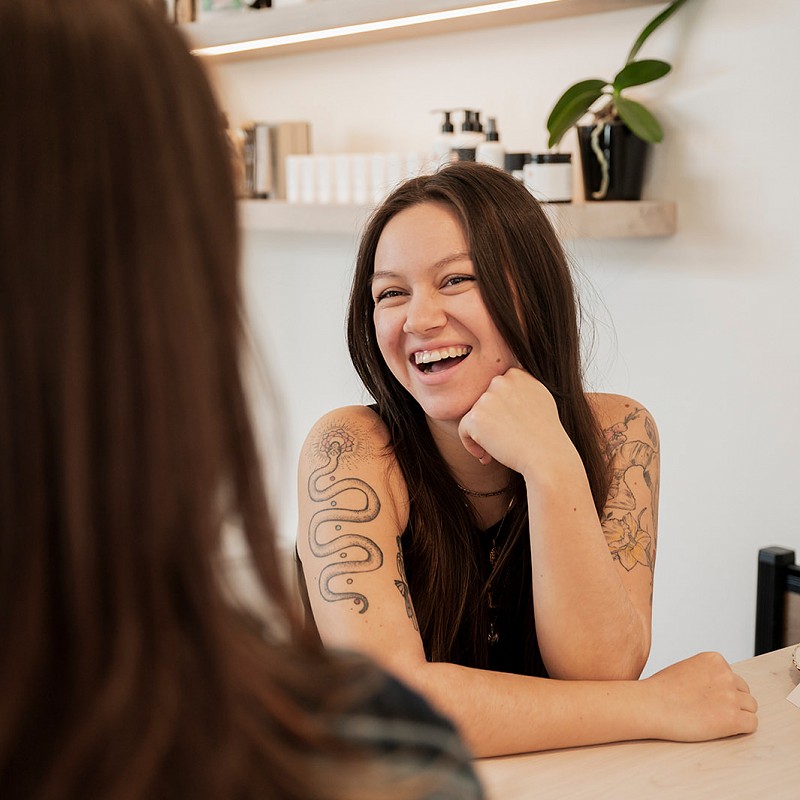 Guest coordinator Rita laughs and talks to a client at the front desk of Violet Hair Lounge